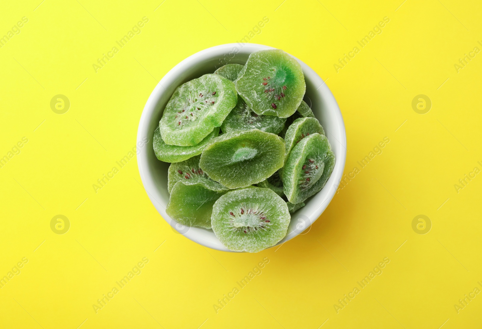 Photo of Bowl with slices of kiwi on color background, top view. Dried fruit as healthy food