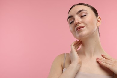 Photo of Beautiful woman touching her neck on pink background. Space for text