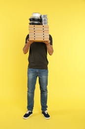 Young courier with different orders on color background. Food delivery service