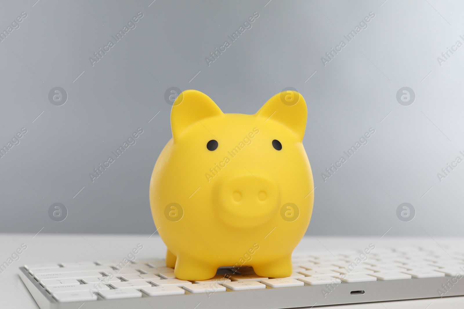 Photo of Yellow piggy bank and keyboard on white table