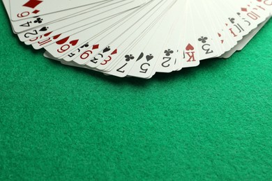 Photo of Fan of playing cards on green table. Space for text