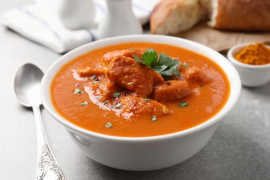 Photo of Bowl of delicious chicken curry on light grey table