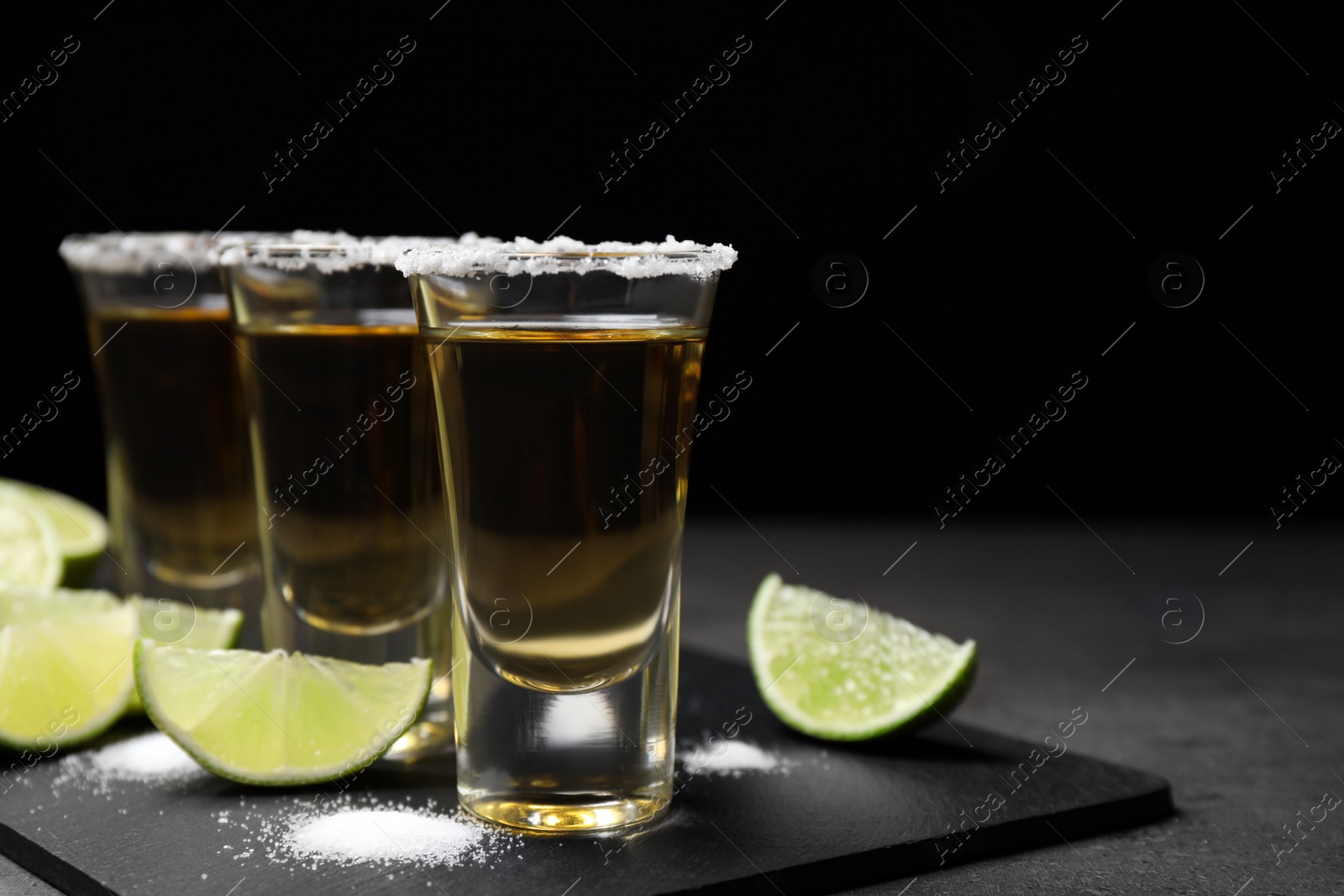 Photo of Mexican Tequila shots with salt and lime on grey table. Space for text