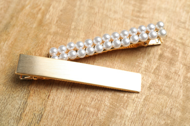 Photo of Stylish gold hair clips on wooden table