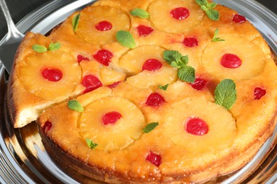Taking piece of delicious cut pineapple pie with cherry and mint on plate, closeup