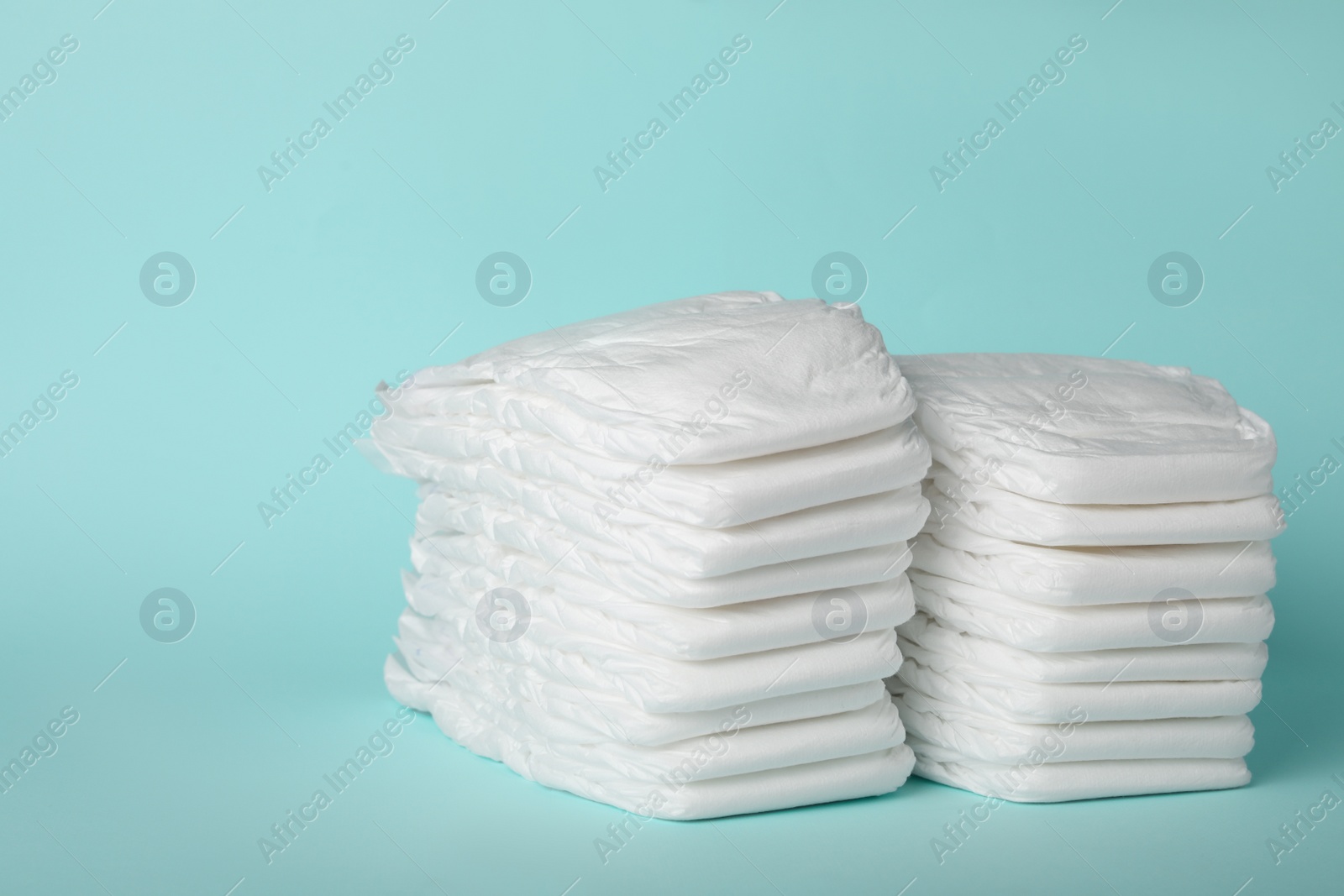 Photo of Stacks of diapers on light blue background