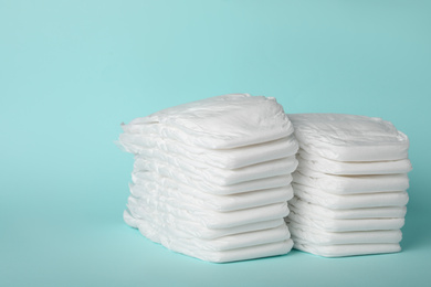Stacks of diapers on light blue background