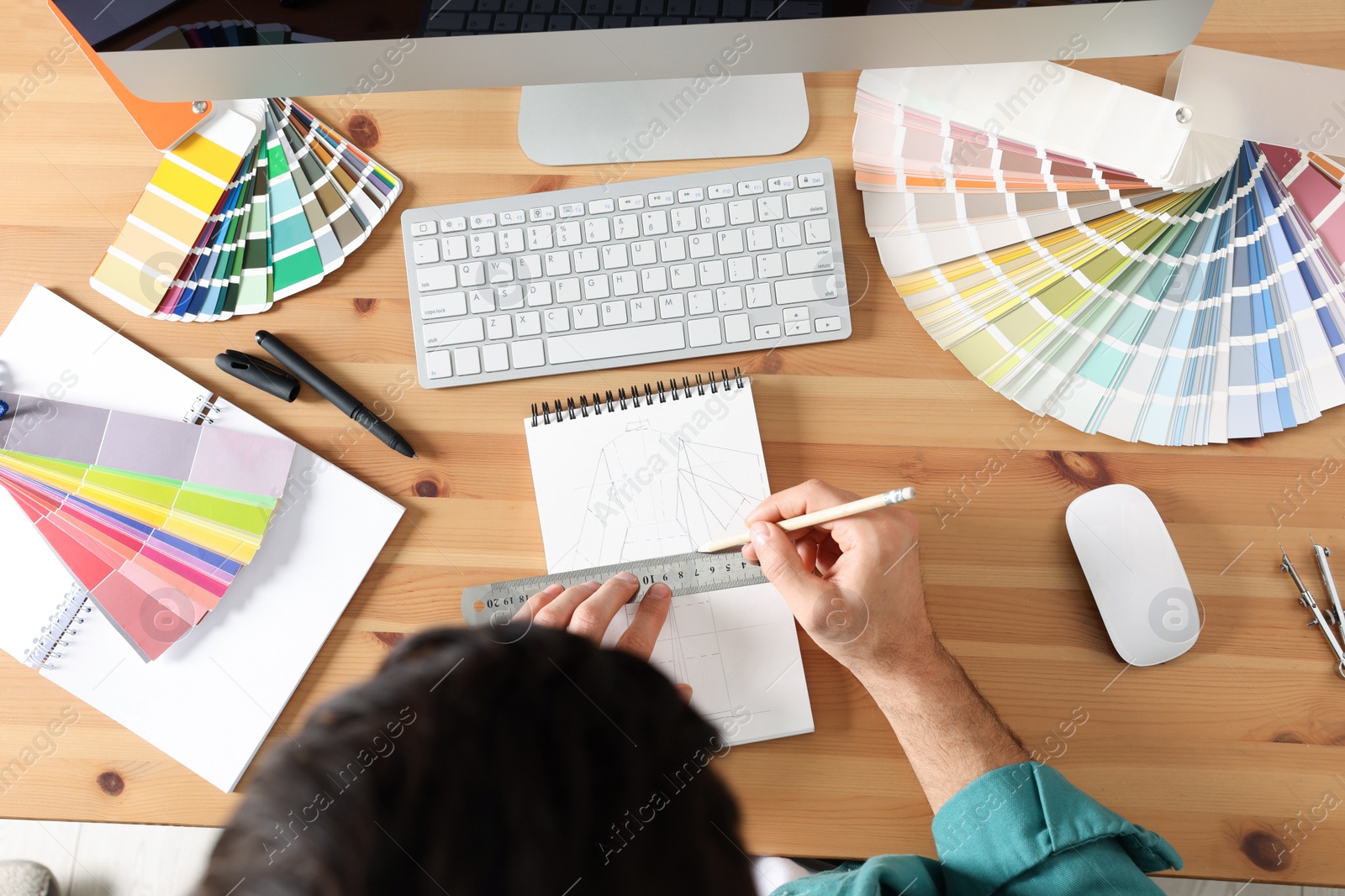 Photo of Man drawing in sketchbook with pencil and ruler at wooden table, top view