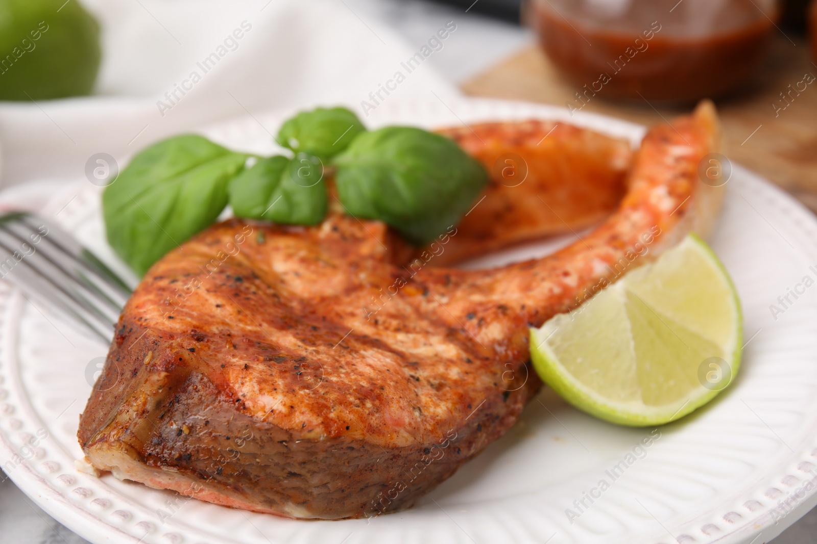 Photo of Freshly cooked fish, lime and basil on table, closeup