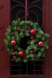 Photo of Beautiful Christmas wreath with red balls hanging on door