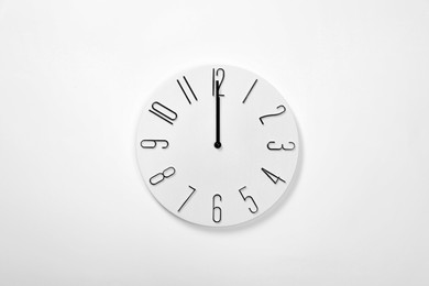 Photo of Stylish analog clock hanging on white wall