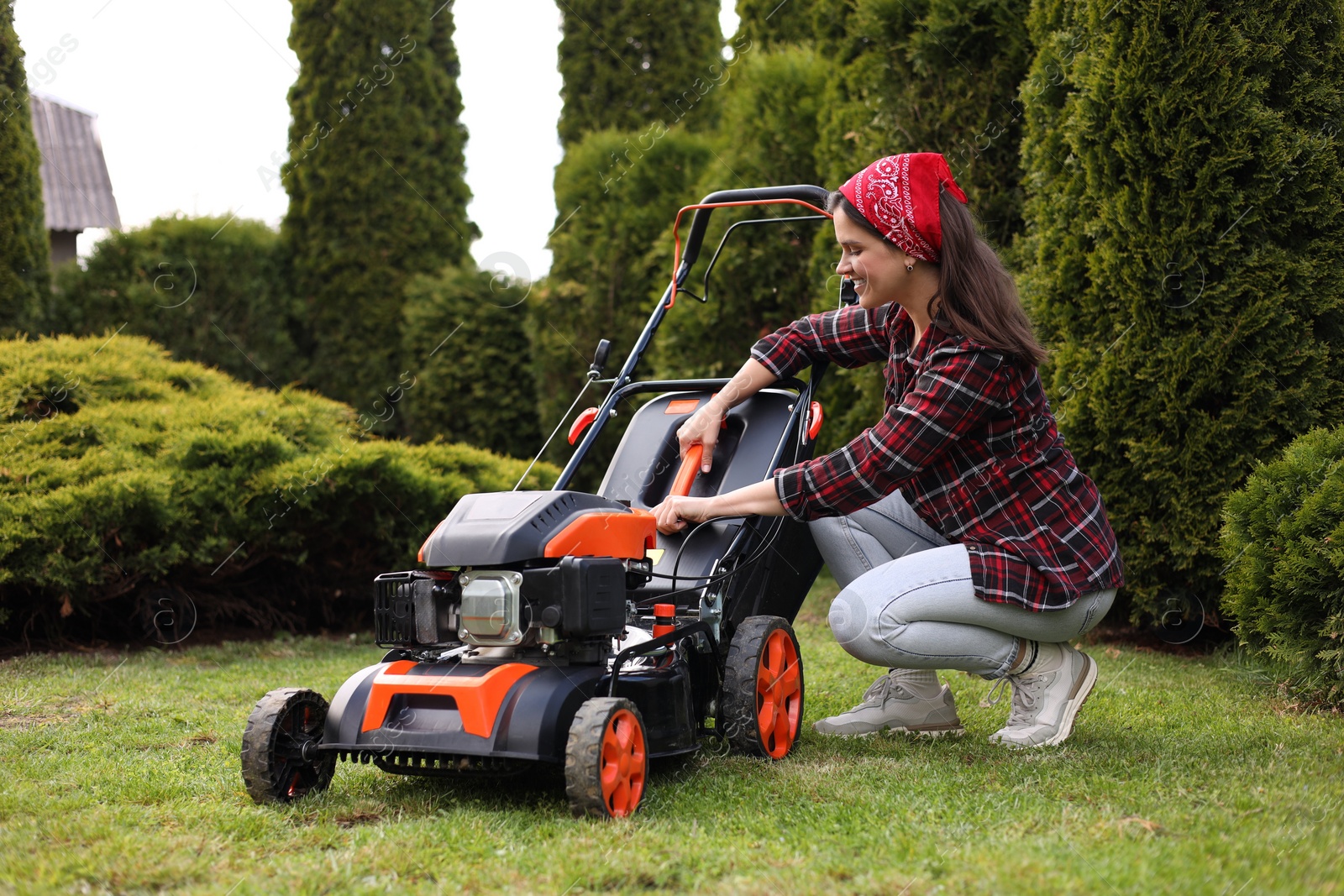 Photo of Smiling woman with modern lawn mower in garden