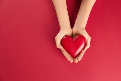 Woman holding decorative heart on color background, top view. Space for text