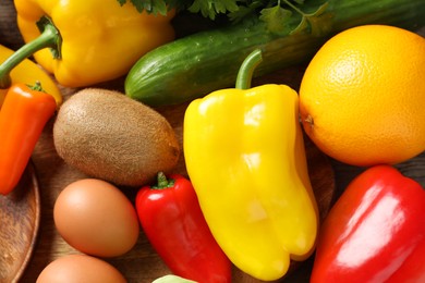 Photo of Healthy meal. Different vegetables and raw eggs on wooden table, flat lay