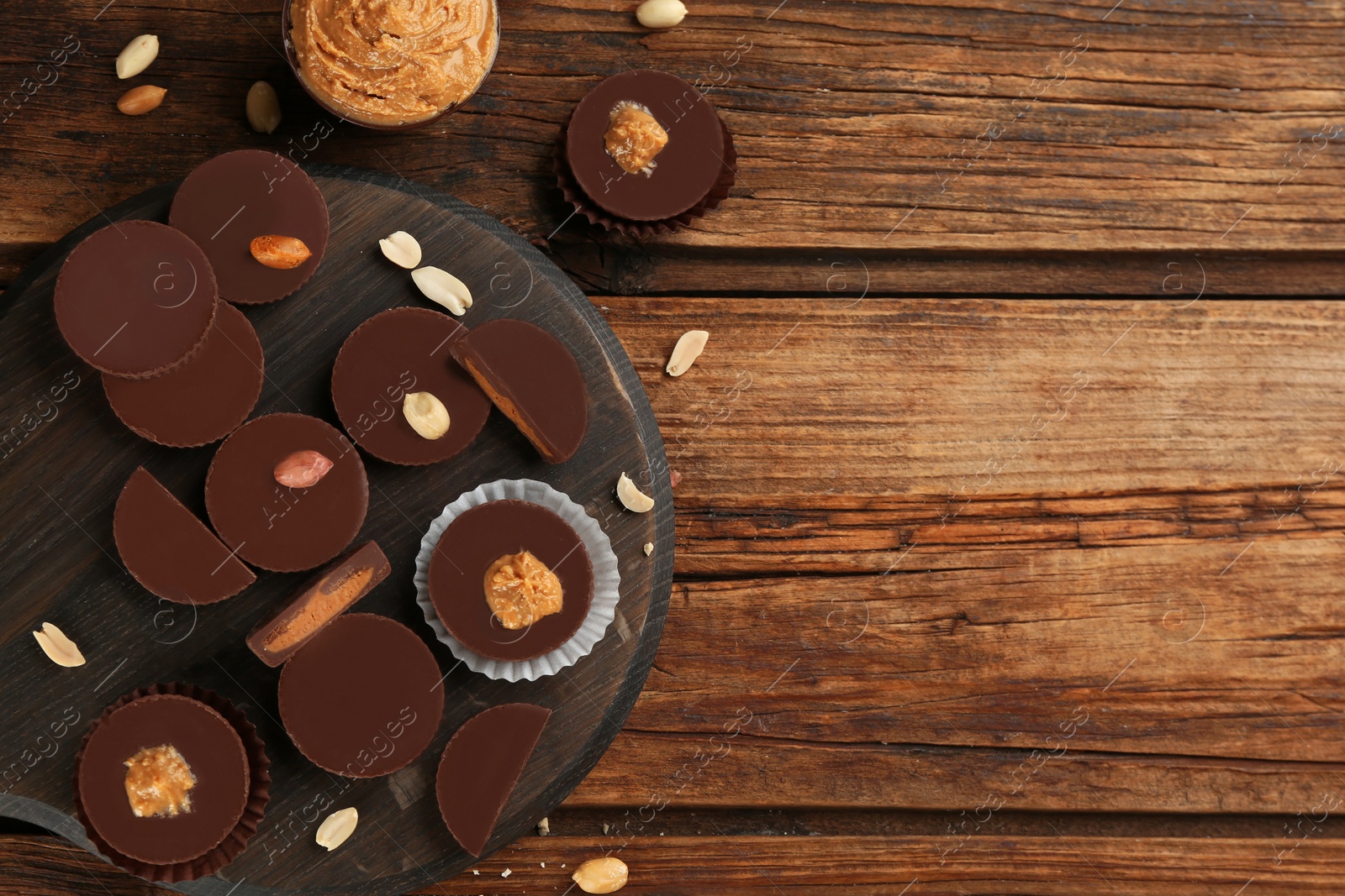 Photo of Flat lay composition with delicious peanut butter cups on wooden table, space for text