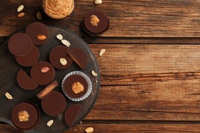 Flat lay composition with delicious peanut butter cups on wooden table, space for text