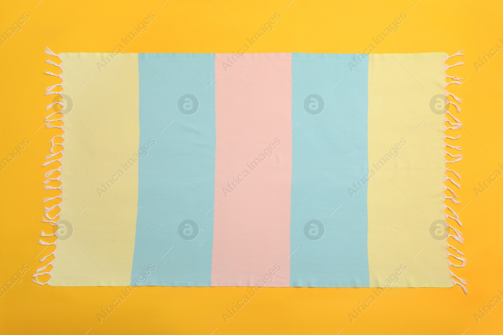 Photo of Striped beach towel on yellow background, top view