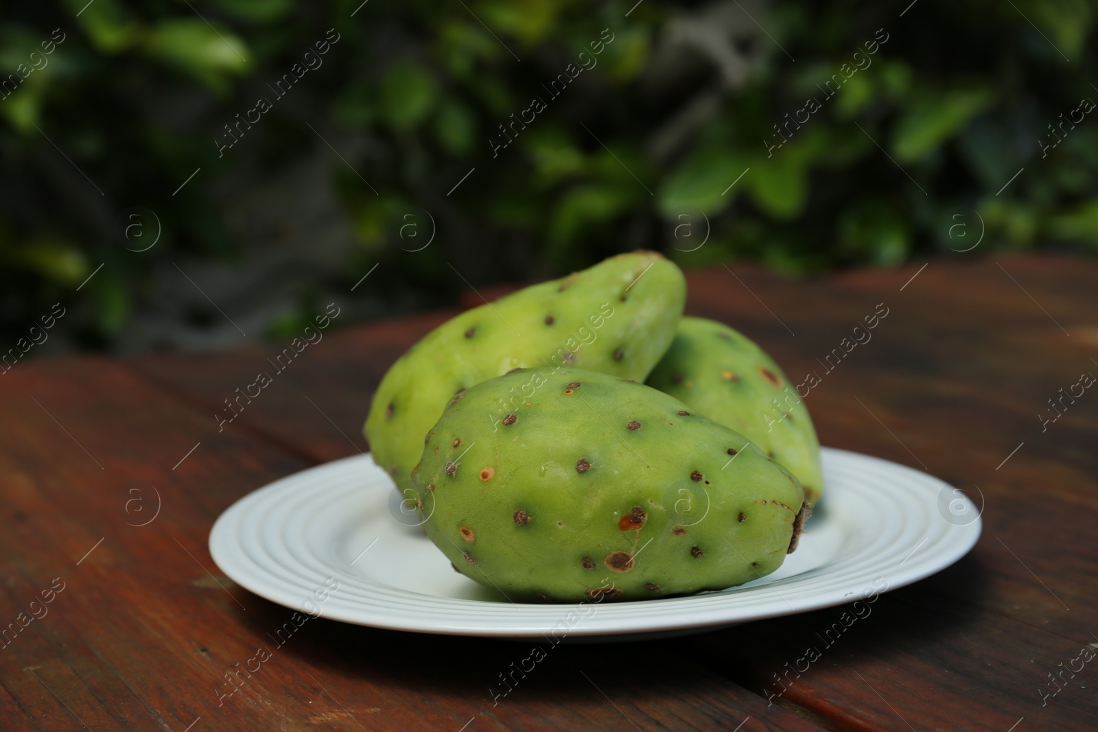 Photo of Tasty prickly pear fruits on wooden table outdoors