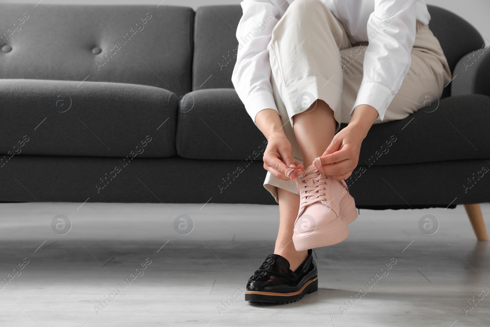 Photo of Woman taking off uncomfortable shoes and putting on sneakers in office, closeup. Space for text