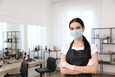 Professional stylist with protective mask in salon, space for text. Hairdressing services during Coronavirus quarantine