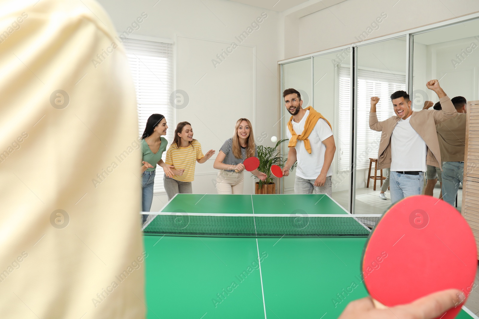 Photo of Happy friends playing ping pong together indoors