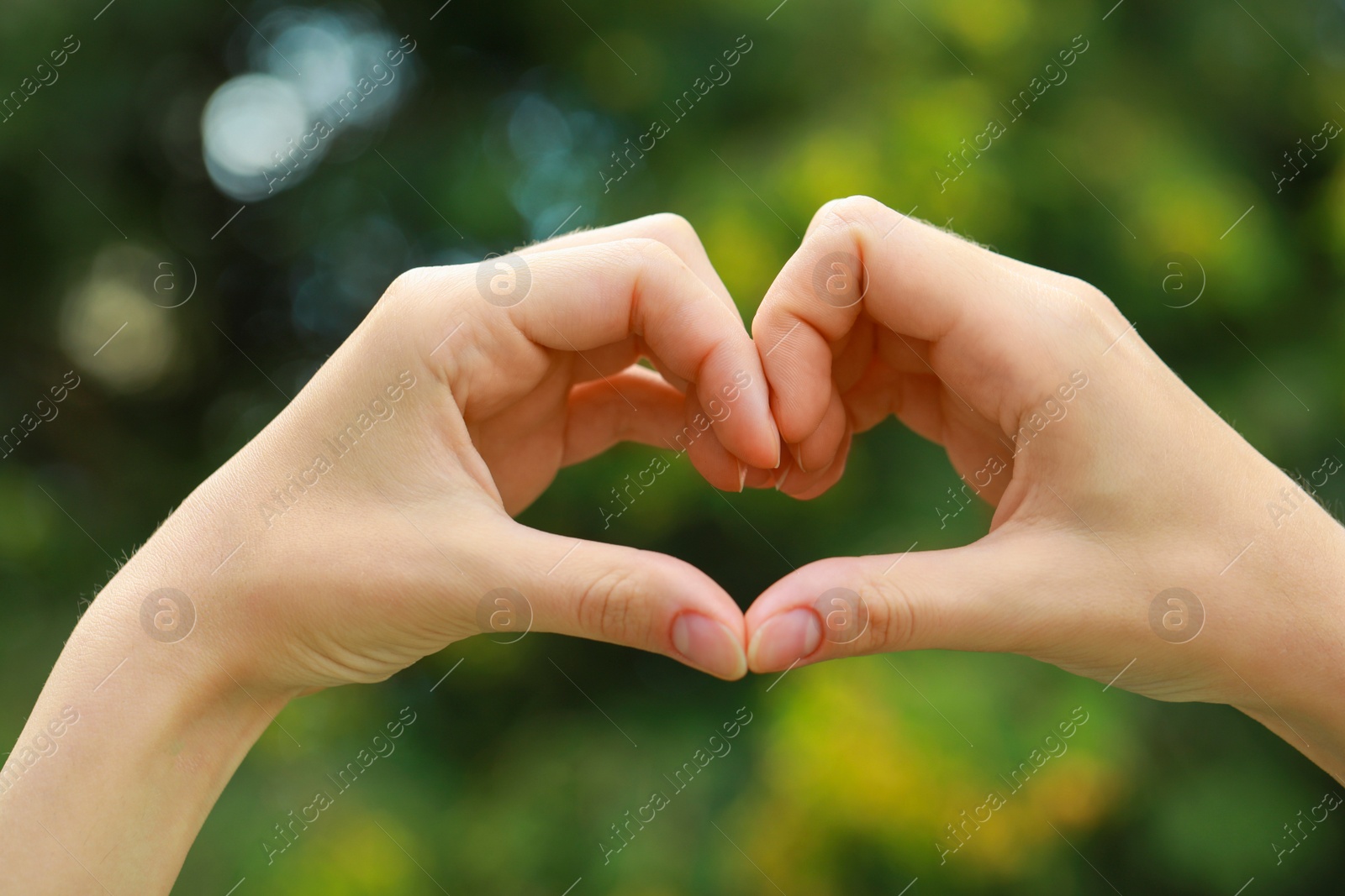 Photo of Woman making heart with hands outdoors, closeup