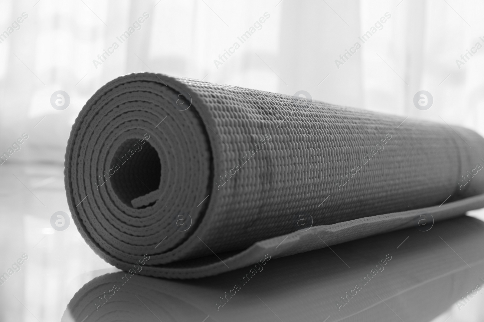 Photo of Rolled karemat or fitness mat on floor indoors, closeup