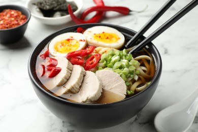 Photo of Delicious ramen in bowl on white marble table, closeup. Noodle soup