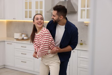 Happy lovely couple dancing together in kitchen