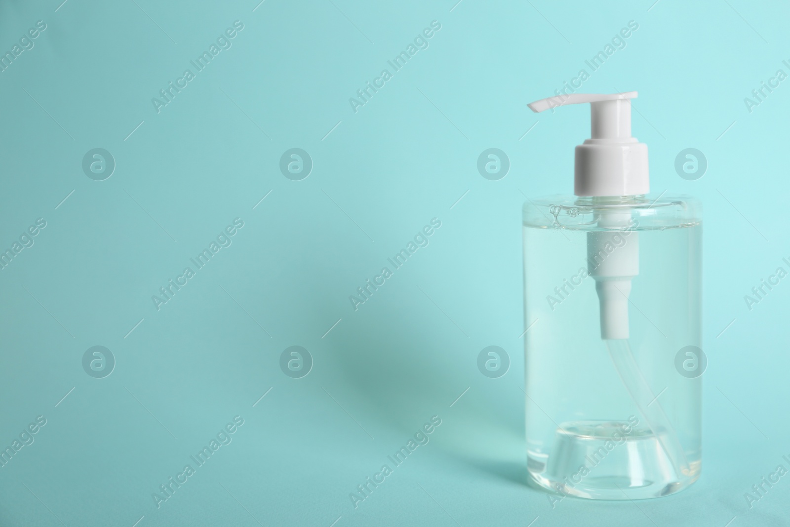 Photo of Dispenser bottle with antiseptic gel on light blue background. Space for text