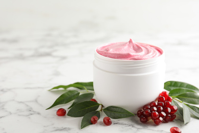 Fresh pomegranate and jar of facial mask on white marble table, space for text. Natural organic cosmetics