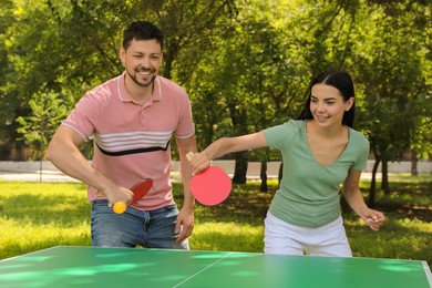 Happy couple playing ping pong in park