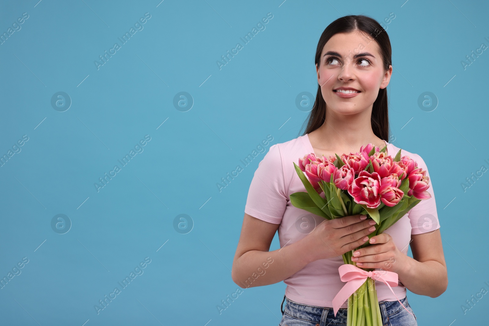 Photo of Happy young woman with beautiful bouquet on light blue background. Space for text