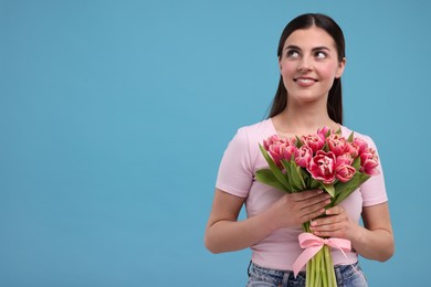 Happy young woman with beautiful bouquet on light blue background. Space for text