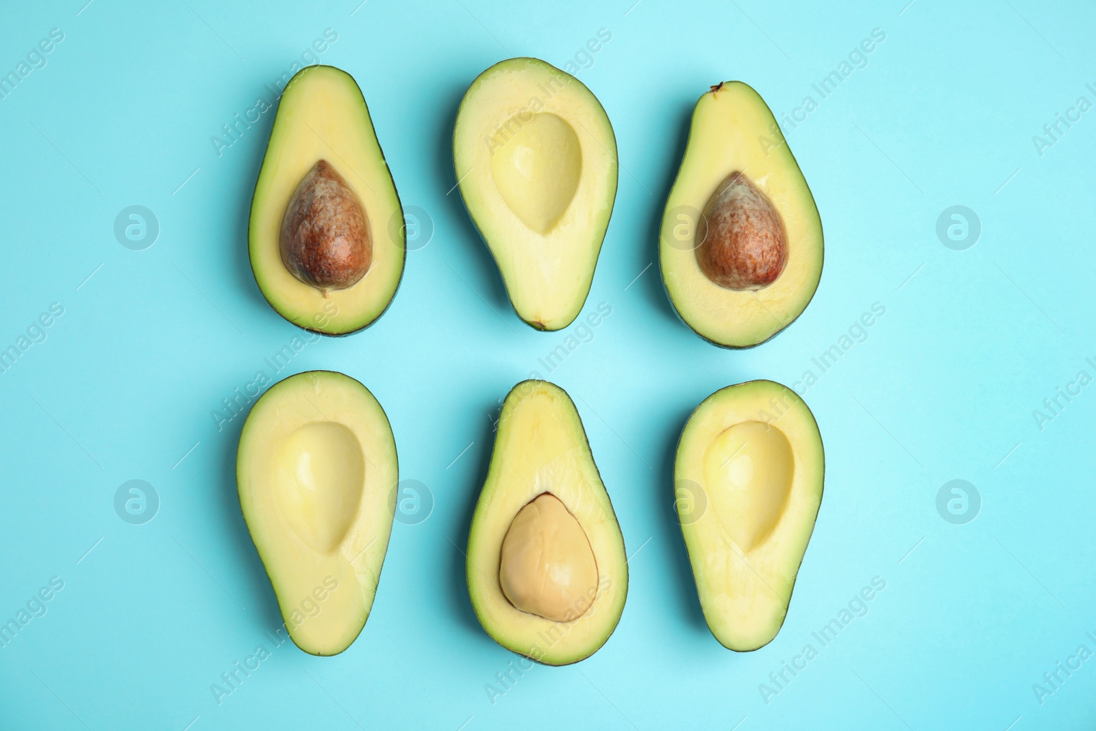 Photo of Cut fresh ripe avocados on blue background, flat lay