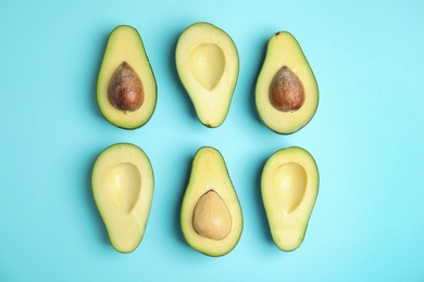 Photo of Cut fresh ripe avocados on blue background, flat lay