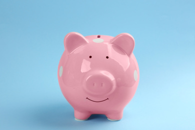 Photo of Cute pink piggy bank on light blue background