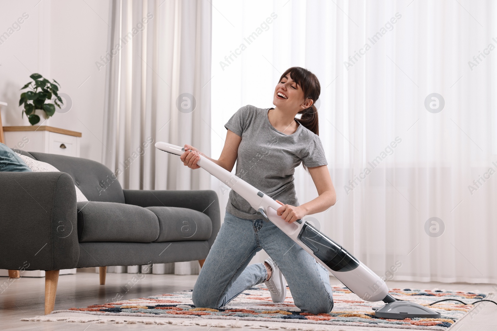 Photo of Happy young housewife having fun while cleaning at home