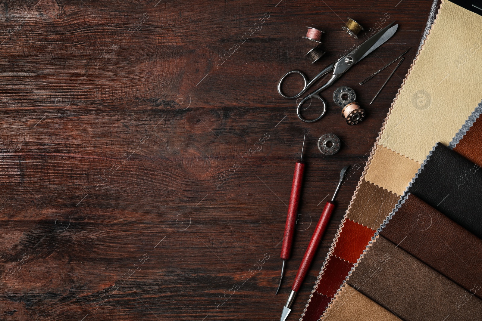 Photo of Flat lay composition with leather samples and tools on  wooden table. Space for text