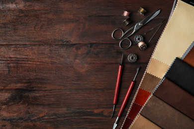 Photo of Flat lay composition with leather samples and tools on  wooden table. Space for text