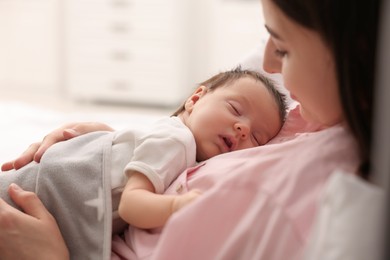 Mother with her sleeping newborn baby in bed at home