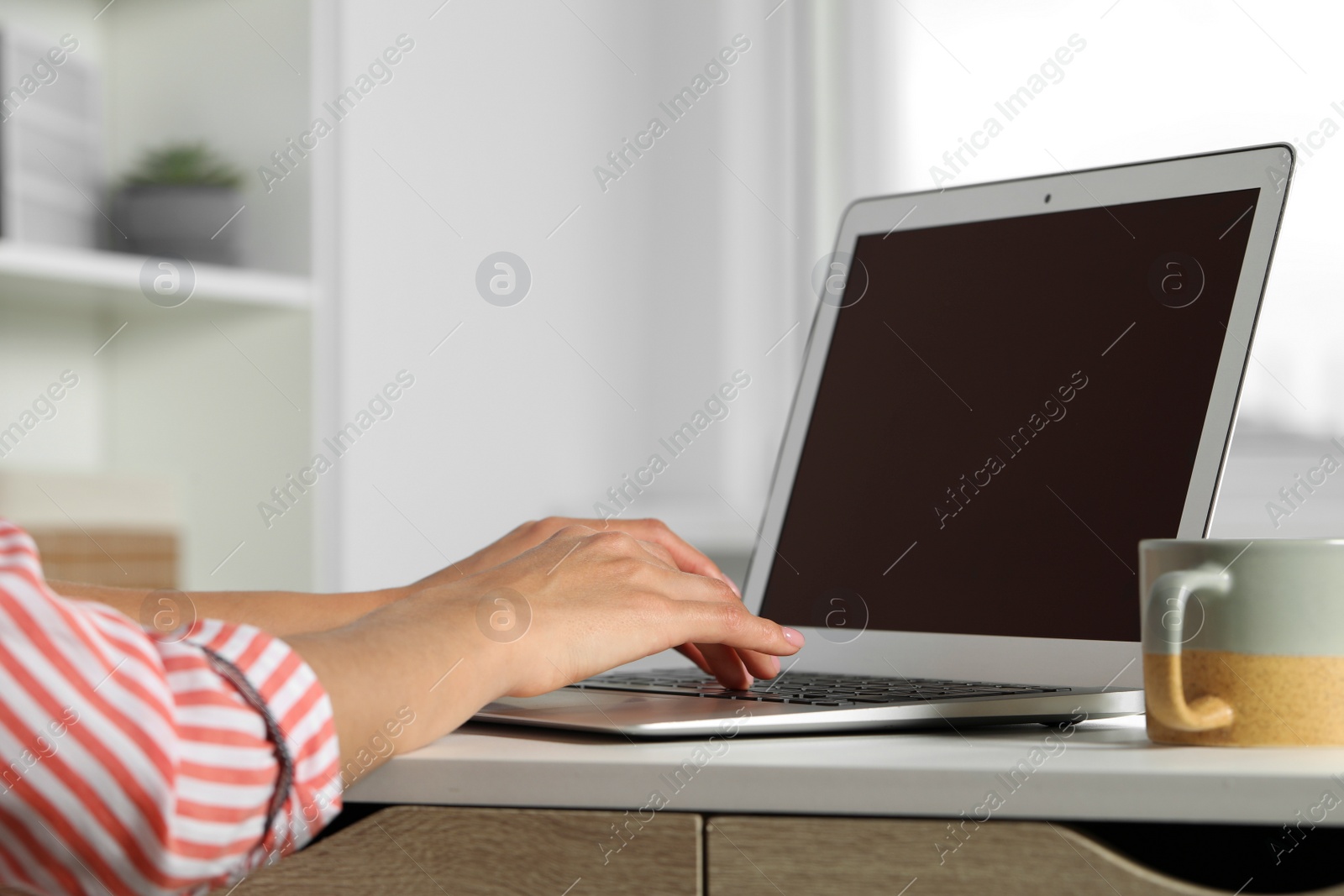 Photo of Young woman working with laptop at workplace in office, closeup