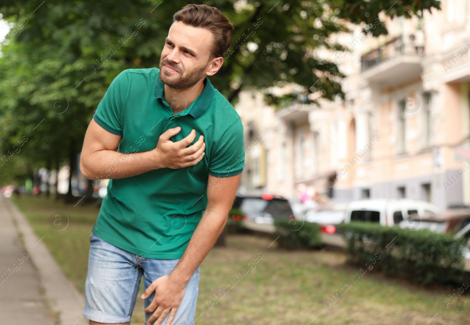 Photo of Young man having heart attack on city street. Space for text