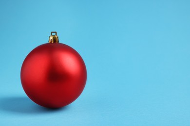 One red Christmas ball on light blue background. Space for text