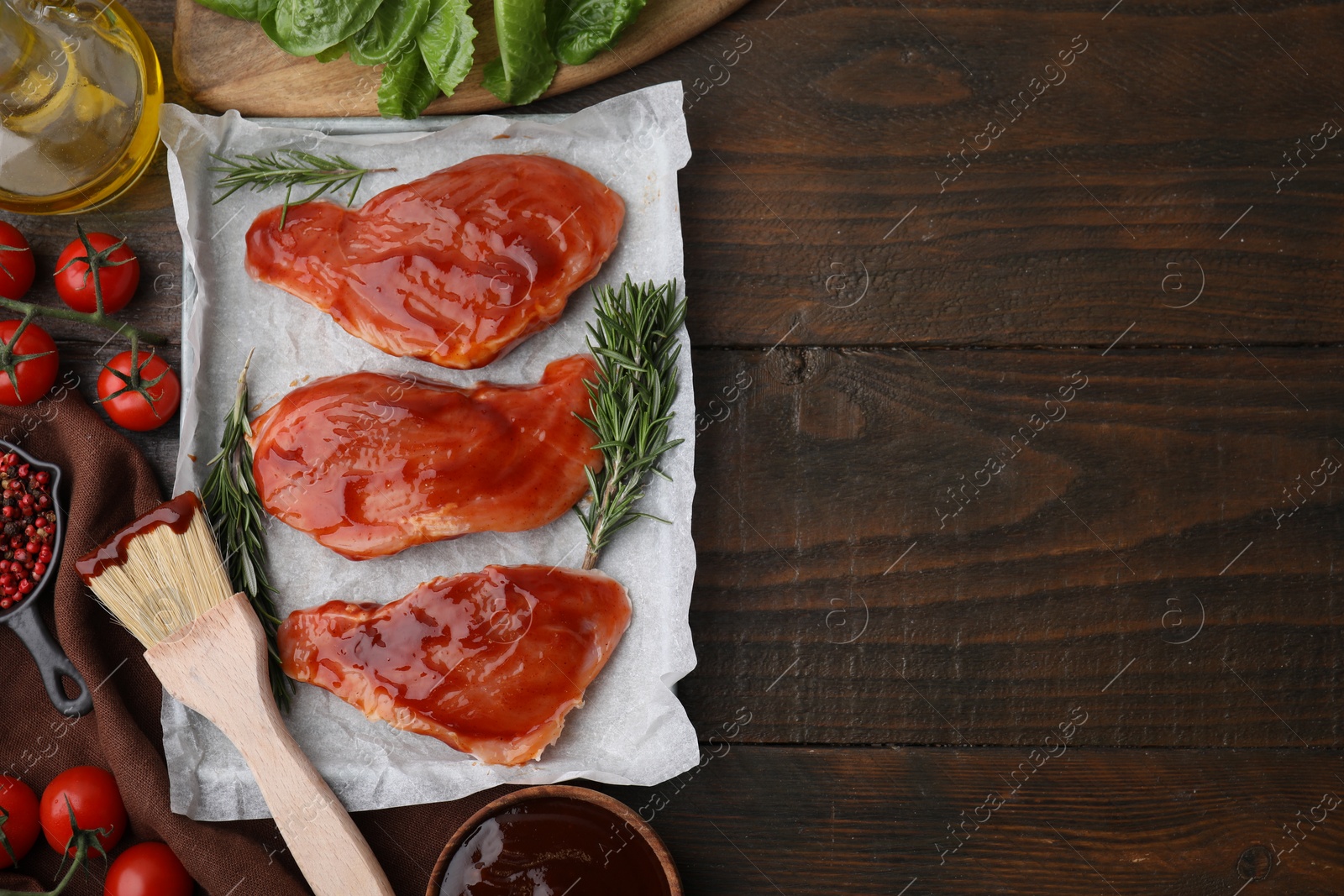 Photo of Flat lay composition with raw marinated meat, products and basting brush on wooden table. Space for text