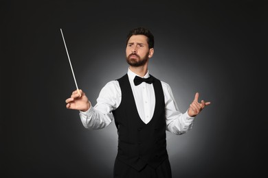 Photo of Professional conductor with baton on black background