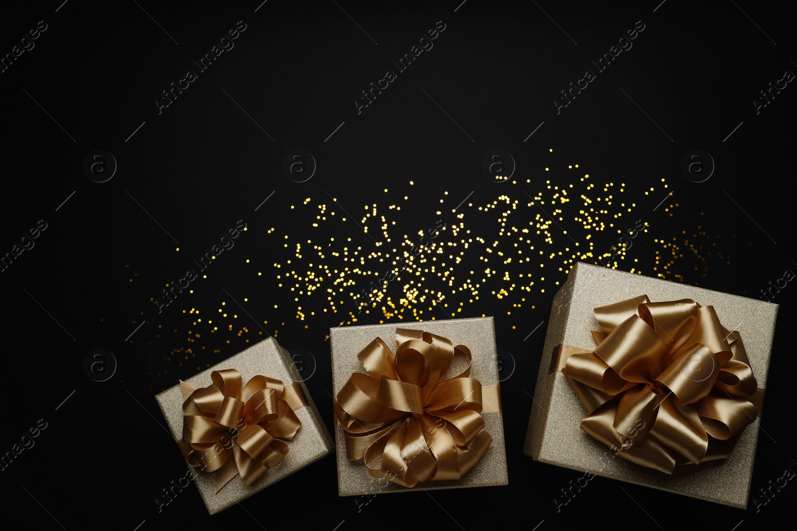 Photo of Golden gift boxes and confetti on black background, flat lay. Space for text