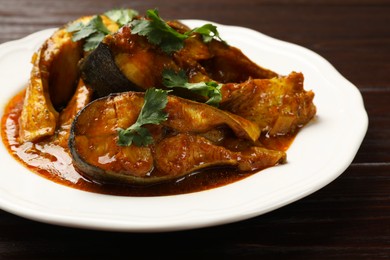 Tasty fish curry on wooden table, closeup. Indian cuisine