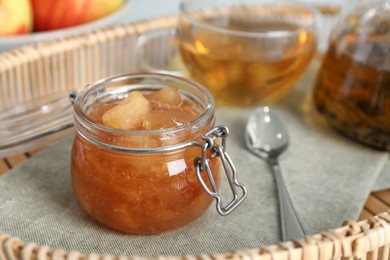 Photo of Delicious apple jam in jar on tray, closeup