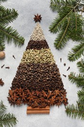 Christmas tree made of different spices and fir branches on gray textured table, flat lay